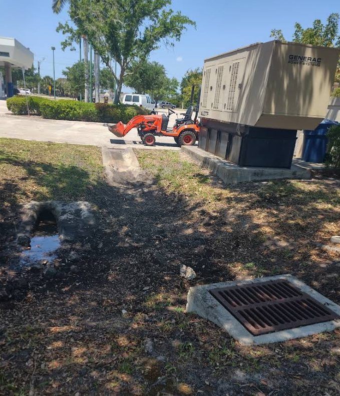 Drainage swale grading with a compact tractor near a generator and storm grate