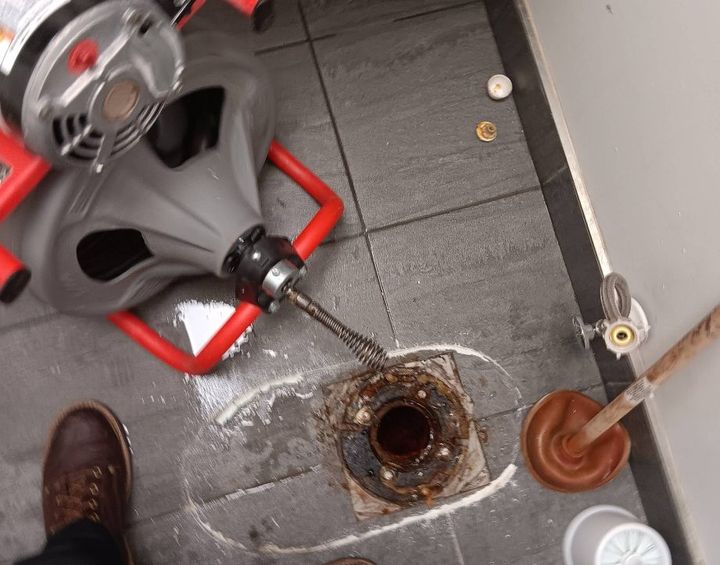 Toilet removed and drain machine snaking the toilet drain line at the closet flange