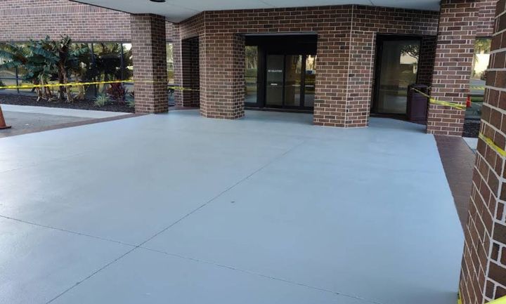 Freshly coated concrete walkway at a brick commercial building entrance