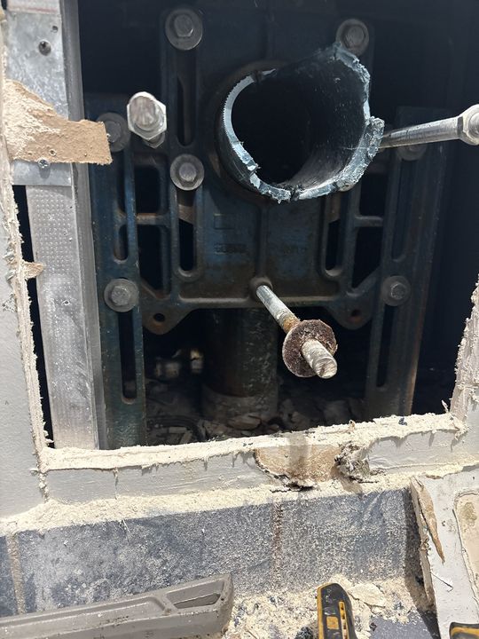 Wall opened to expose a cast-iron wall-hung toilet carrier and drain
